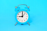 Blue alarm clock on blue background close up 9 a.m., 9 p.m. Time concept.