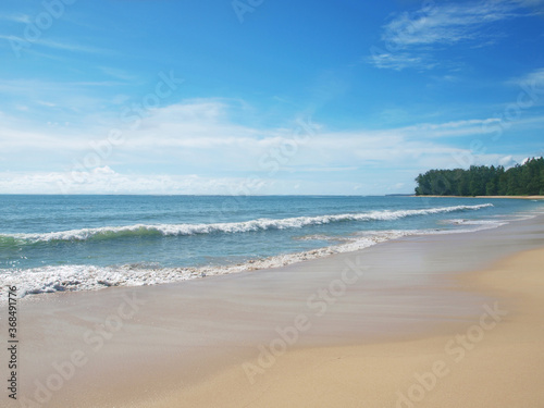 Sky with beautiful white clouds over the blue sea. View to the open ocean and green cliff. Popular resort  tropical island. Sandy beach. Seascape. Paradise. Water and waves. Thailand  Phuket