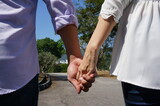 A couple holding hands, wearing white shirts