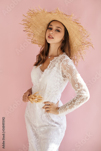 Portrait on a pink background in a straw hat happy