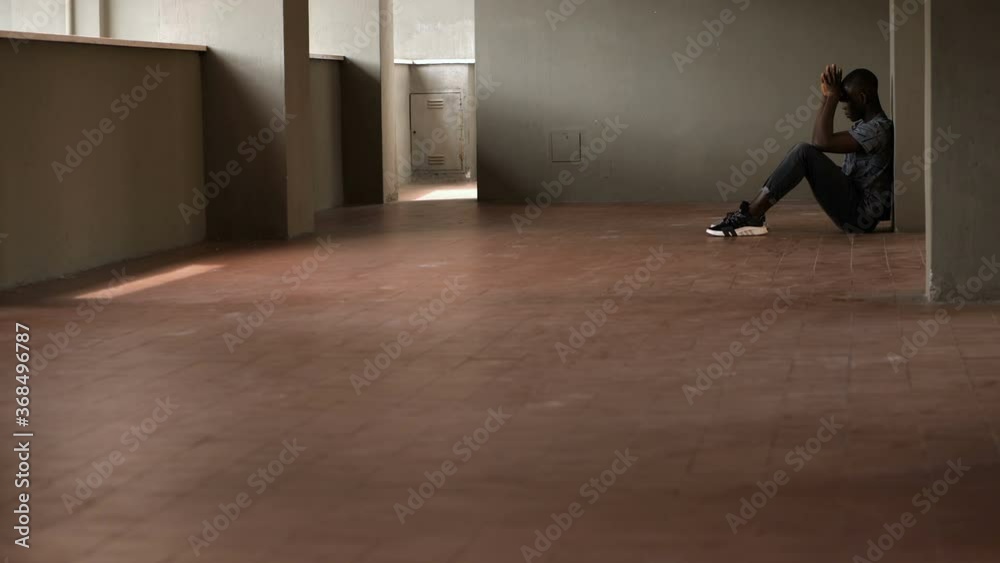 depression, solitude - black man sitting on the ground in the empty apartement depression, solitude - black man sitting on the ground in the empty apartement