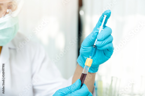 Researcher or scientists loads liquid into blood sample in test tube. Researchers are developing vaccines and medicine to treat the COVID-19 virus.