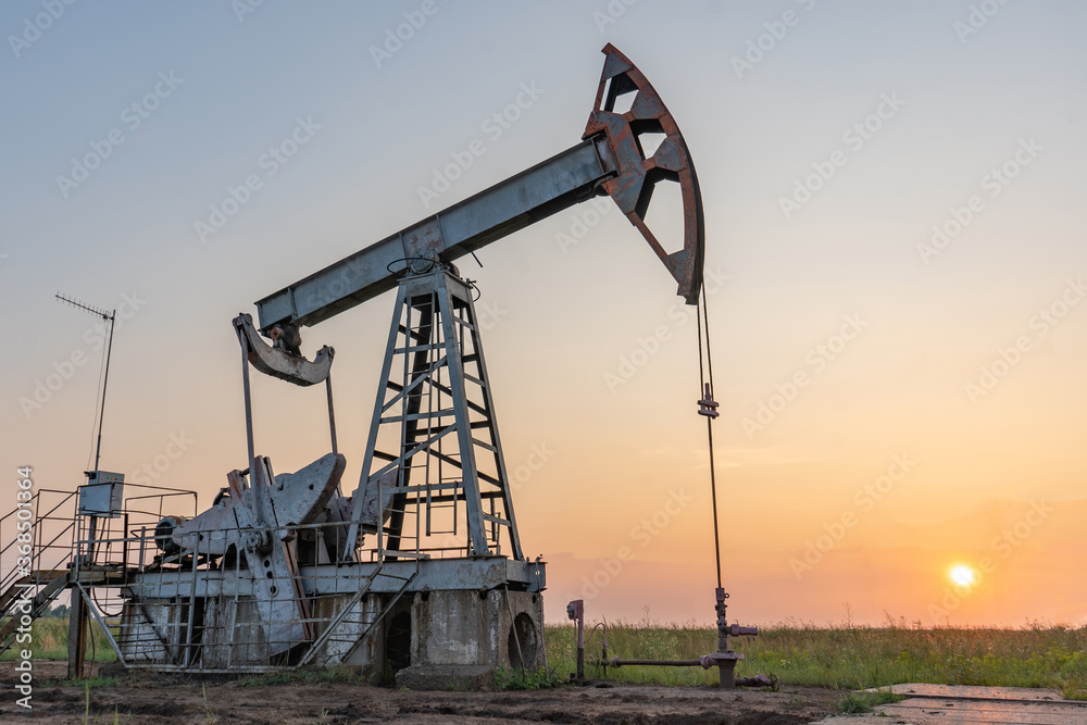 Oil pump at sunset in the field Oil pump at sunset in the field