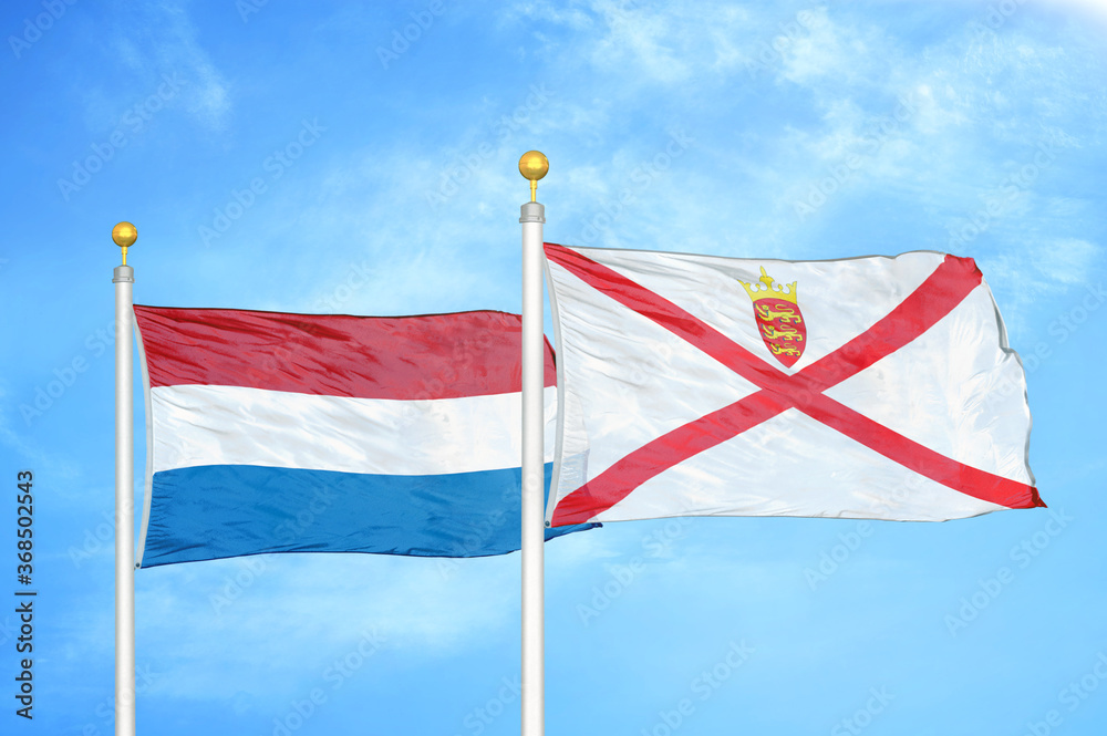 Fototapeta premium Netherlands and Jersey two flags on flagpoles and blue sky