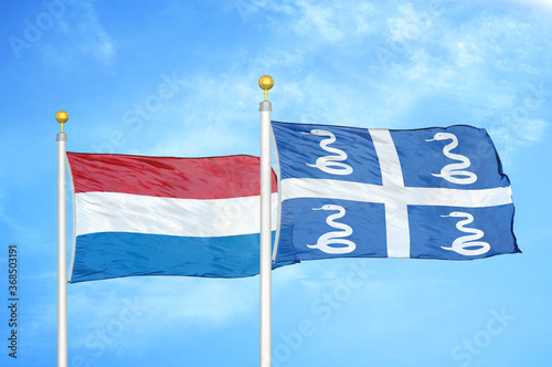 Netherlands and Martinique snake two flags on flagpoles and blue sky