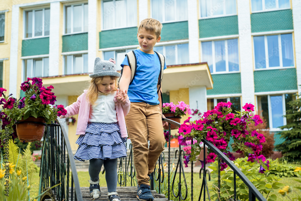 Happy children playing in the school yard at the day time.Outdoors summer walk, flowering courtyard, green park. Concept of happy friendly sister and brother. Happy children playing in the school yard at the day time.Outdoors summer walk, flowering courtyard, green park. Concept of happy friendly sister and brother.