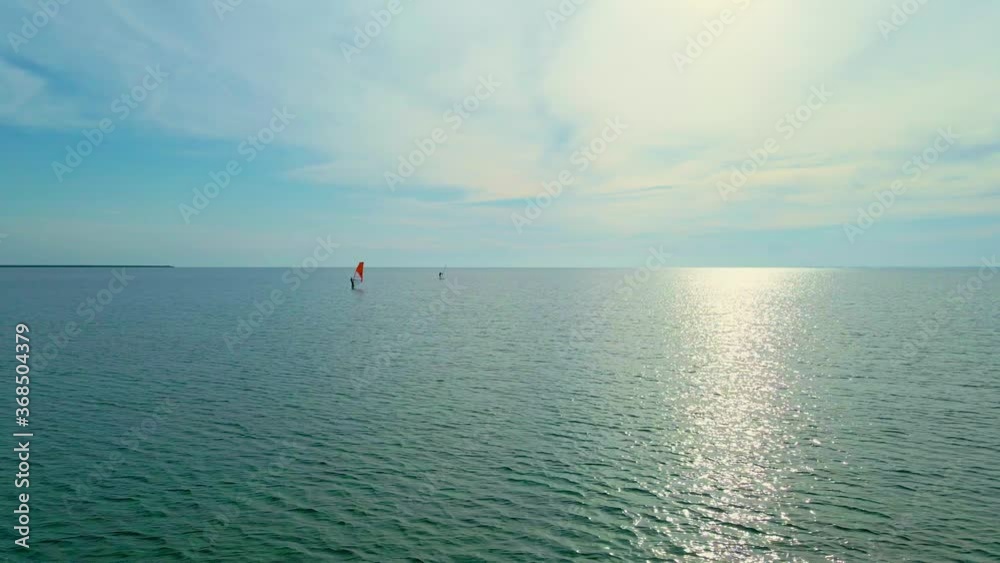 wind surfing. aerial view calm sea surface with sun reflection and two windsurfers. shot from above top view 4k 60fps slowmotion wind surfing. aerial view calm sea surface with sun reflection and two windsurfers. shot from above top view 4k 60fps slowmotion
