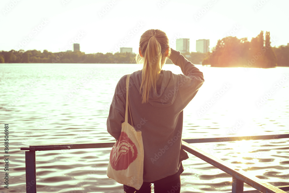 Silhouette of a beautiful young girl watching the sunset. Wearing  eco-bag .