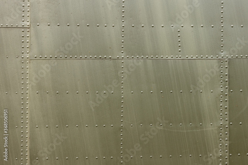 Details of the fuselage of an old aircraft. Old camouflage surface with exfoliated paint and rivets on a military aircraft.