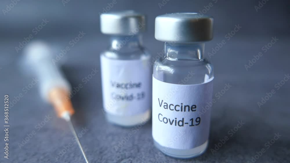 Close up of coronavirus vaccine and syringe on black background Close up of coronavirus vaccine and syringe on black background