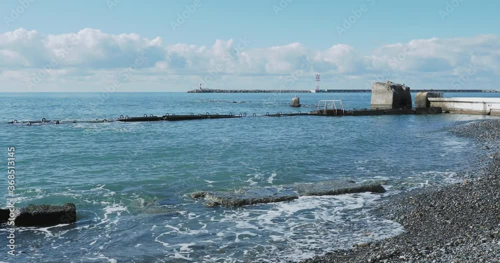 Seagull sits on rock. Lighthouse in port of Sochi, Russia. Silhouettes of seagulls on rocks and tranquil sea surf. Seagull sits on rock. Lighthouse in port of Sochi, Russia. Silhouettes of seagulls on rocks and tranquil sea surf.