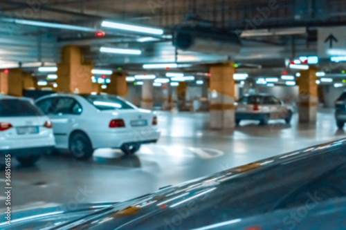 Garage car blurred. Car lot parking space in underground city garage. Empty road asphalt background in soft focus. Concrete skeleton for parking car. © Maksym