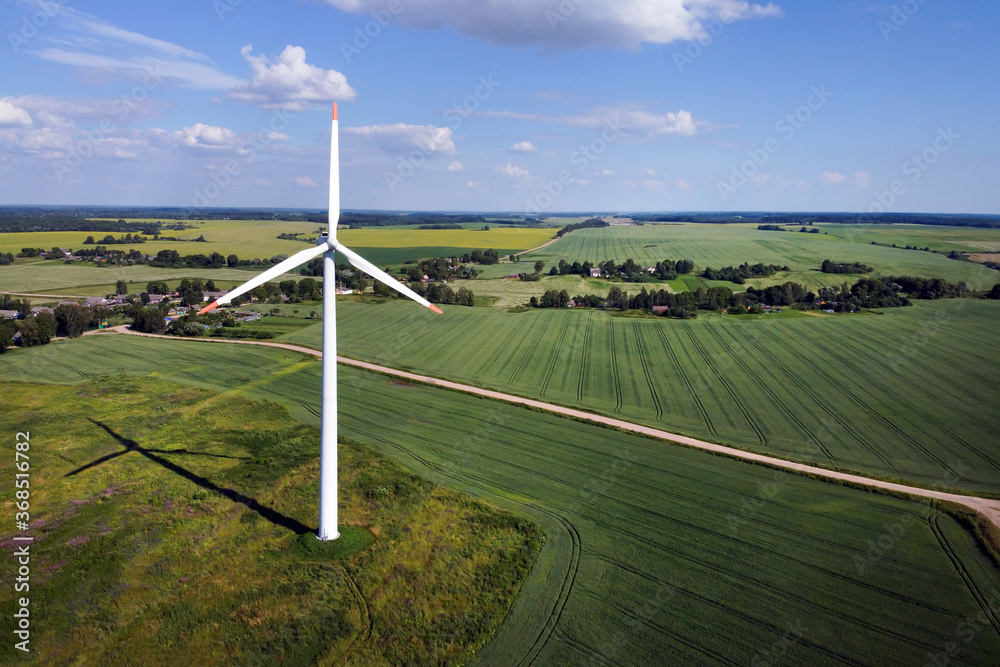 Aerial view of wind turbine and agricultural field, summer rural landscape. Wind power, sustainable and renewable energy Aerial view of wind turbine and agricultural field, summer rural landscape. Wind power, sustainable and renewable energy