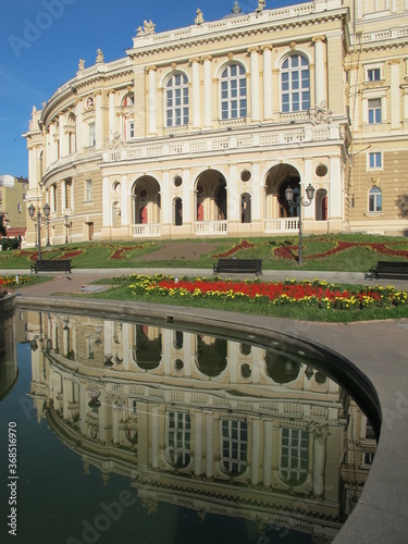 The old building of the theater, mirror reflection in the water, Odessa. The historic building of the Odessa Opera and Ballet Theater is reflected in calm waters, architects Fellner and Helmer, the st photo