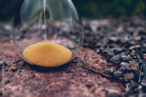 Close up of golden glass sand watch on the stone in nature. photo