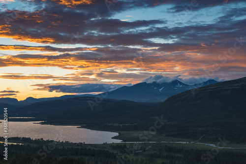 Mountain tops of Rondane in Norway seen from a view point. Beautiful sunset colors. Part of a lake is also seen.