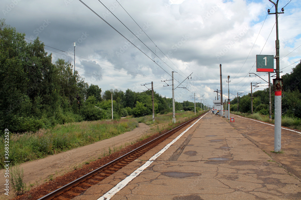Railway platform, rails extending into the distance, waiting for a train, country landscape