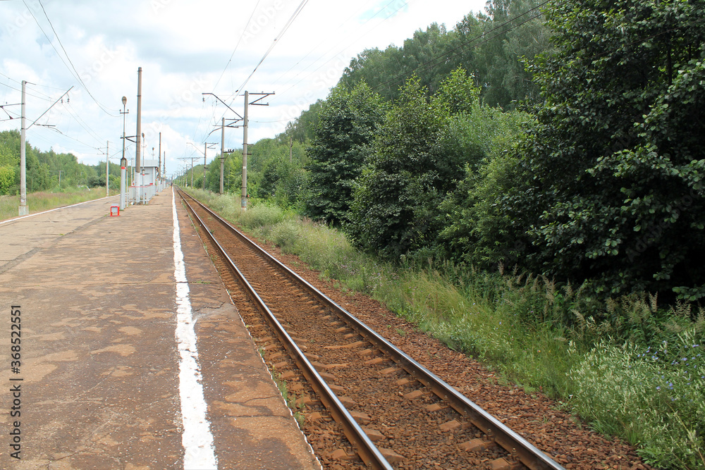 Railway platform, rails extending into the distance, waiting for a train, country landscape