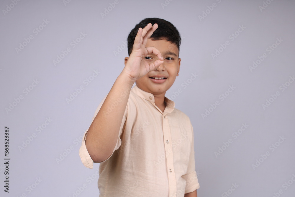 Cute and smart Indian boy showing all good or beautiful hand signal. This front facing photo of boy giving his approval for thing by hand gesture.