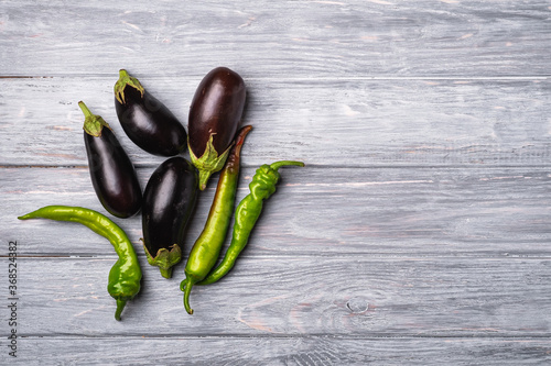 Hot spicy green chili pepper and fresh ripe eggplant vegetables, wooden board background, top view copy space