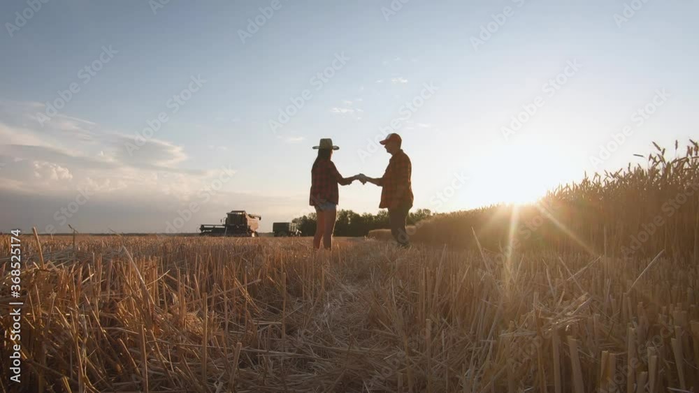 Farmers handshake over the wheat crop in harvest time. Team farmers stand in a wheat field with tablet at sunset. Partnership concept. Farmers handshake over the wheat crop in harvest time. Team farmers stand in a wheat field with tablet at sunset. Partnership concept.