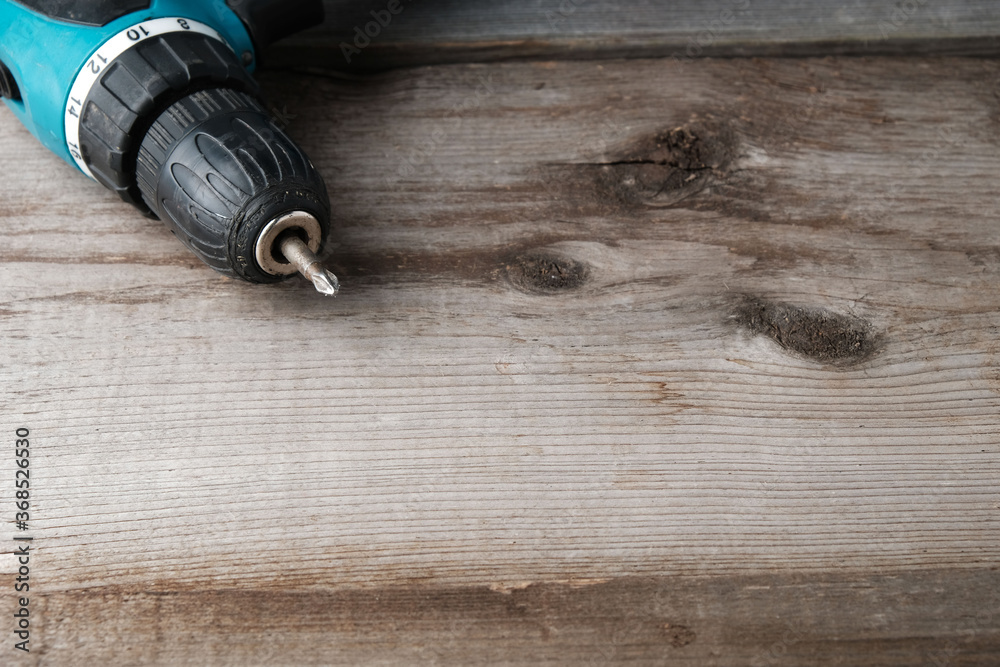 Cordless drill screwdriver on an old wooden background with a place to add text, copy space