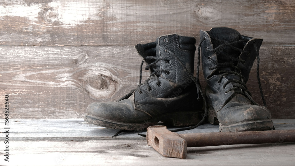 Old dirty shoes boots boots and hammer on a wooden background Old dirty shoes boots boots and hammer on a wooden background