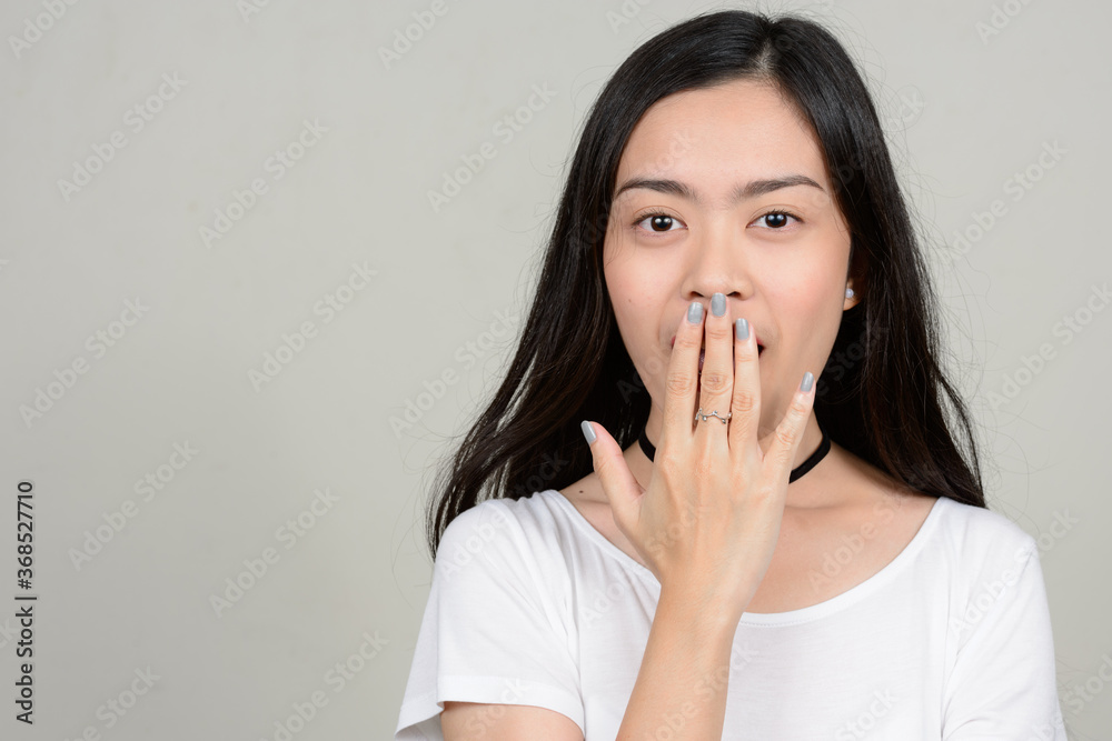 Portrait of young beautiful Asian woman against white background Portrait of young beautiful Asian woman against white background