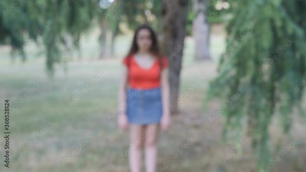 steady cam on young sad woman ta park looking at camera - blurred