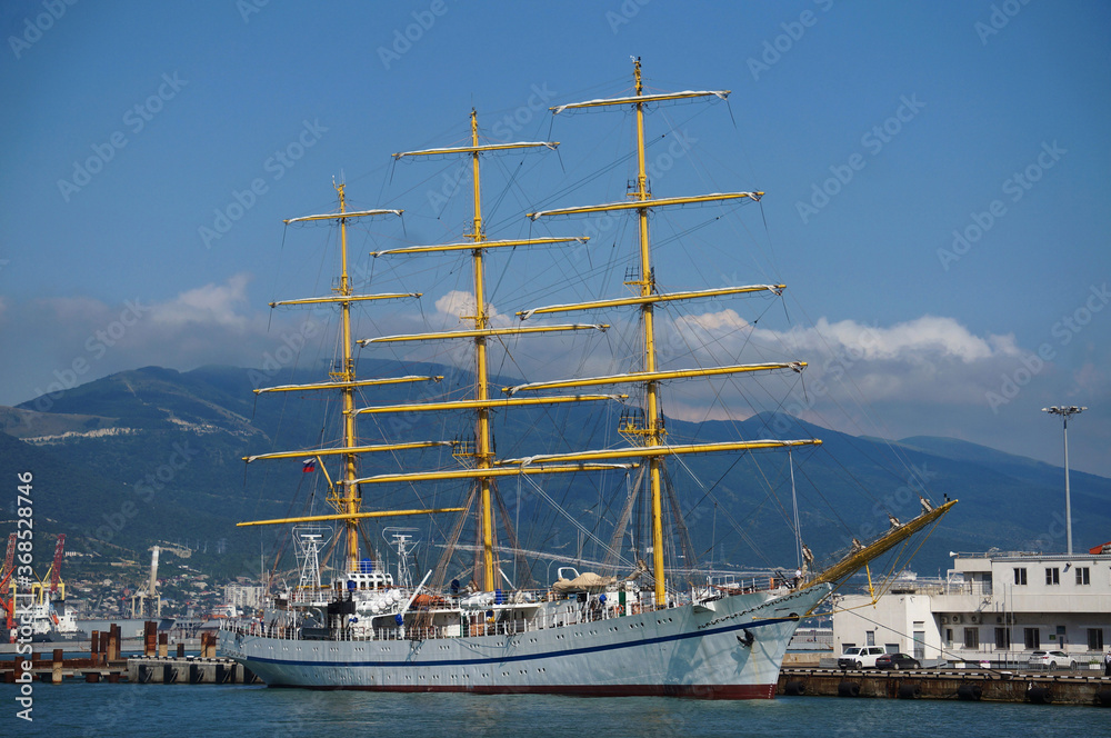 A beautiful frigate with masts stands in the port city of Novorossiysk.