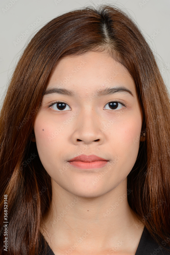 Portrait of young beautiful Asian woman against white background Portrait of young beautiful Asian woman against white background