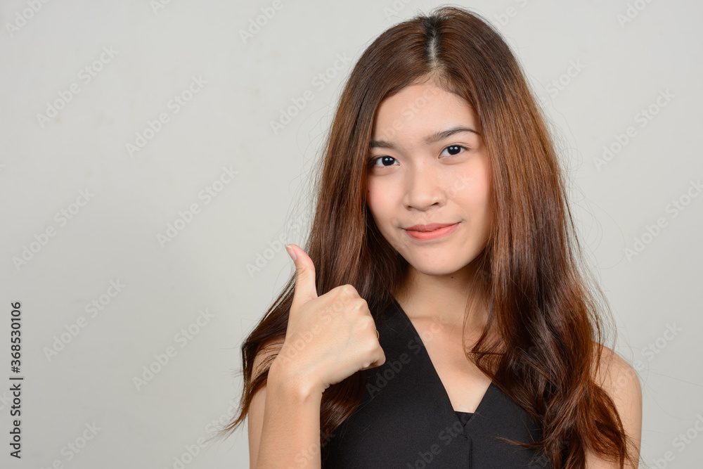 Portrait of young beautiful Asian woman against white background