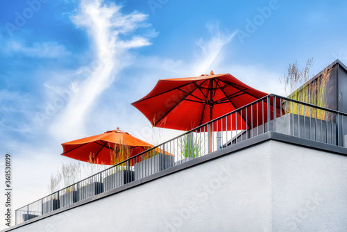 Fototapeta Naklejka Na Ścianę i Meble -  View from below on a modern outdoor terrace with orange parasols and plants