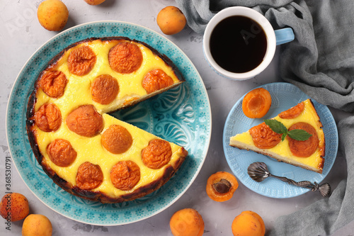 Bild auf Leinwand Cheesecake with apricots with a cut out piece, located on a blue plate and cup o