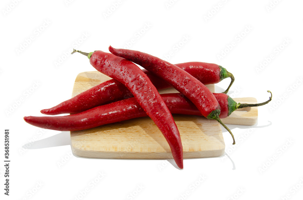 Four red hot chili peppers on a wooden kitchen chopping Board. Isolated on a white background. Side view, no people. Four red hot chili peppers on a wooden kitchen chopping Board. Isolated on a white background. Side view, no people.