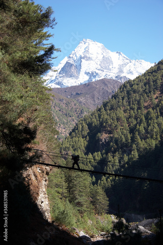 Porter crossing rope bridge at Everest trail in Himalaya, Nepal