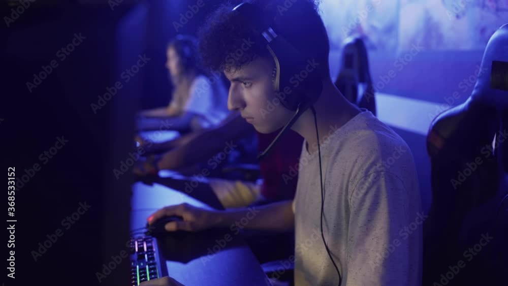 Young man spending time in modern e-sport club playing shooter video game Young man spending time in modern e-sport club playing shooter video game