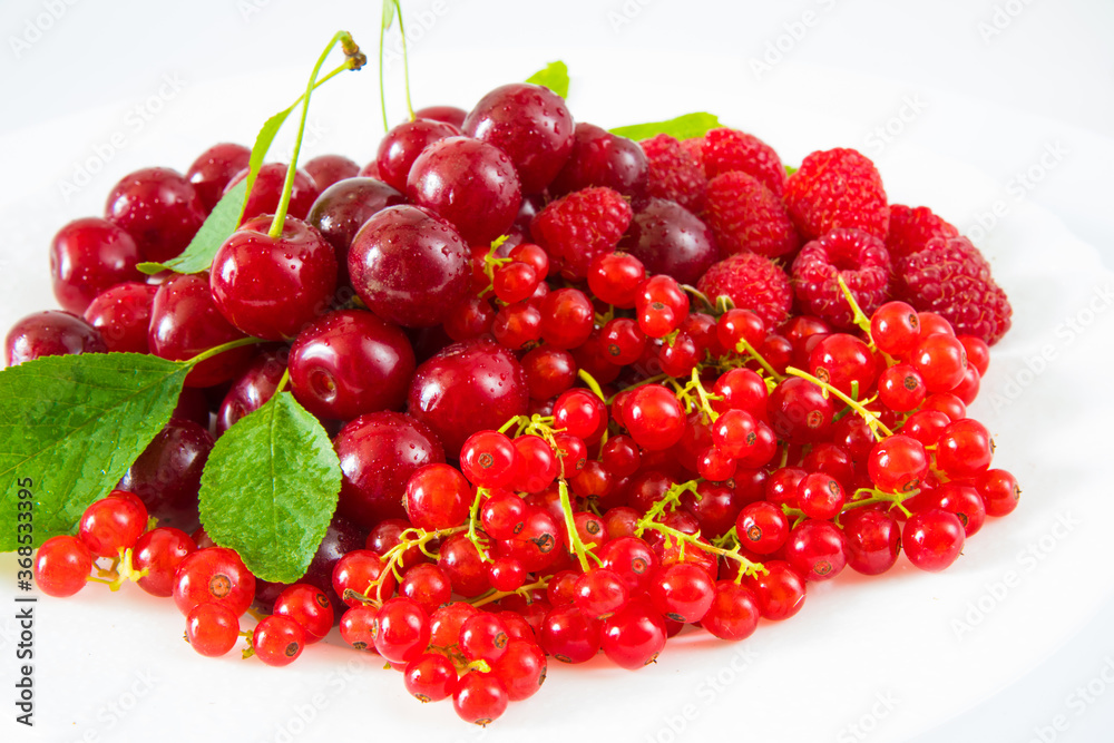 Assorted red fresh berries on a plate on a white background. Assorted red fresh berries on a plate on a white background.