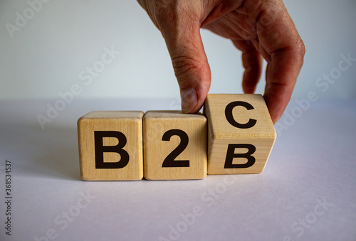 Business to Business or Busness to Consumer. Hand turns a cube and changes the expression 'B2C' to 'B2B' or vice versa. Business concept. Beautiful white background, copy space.