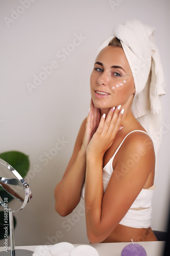 portrait of a beautiful woman applying face cream for skin care