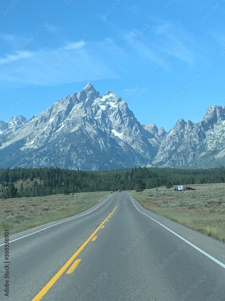Driving on an empty highway with the Grand Teton mountains in the background