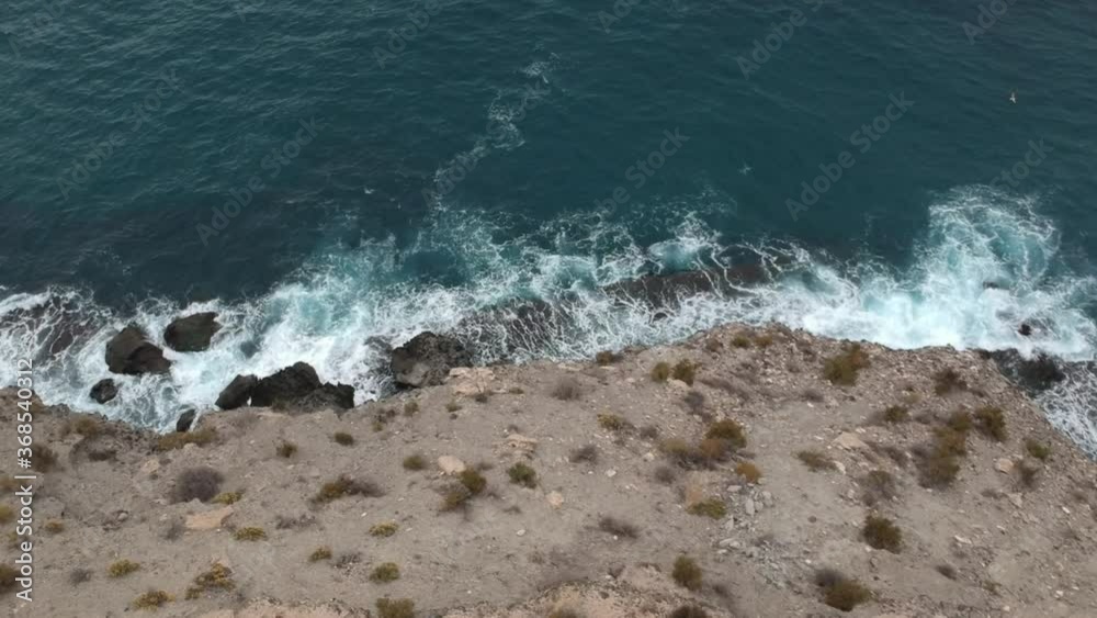 Aerial drone POV of waves breaking on cliff, Playa La Carolina, Murcia, a tourist destination in Spain Aerial drone POV of waves breaking on cliff, Playa La Carolina, Murcia, a tourist destination in Spain