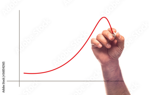 Fotografie A hand drawing a line chart in upward and then downward trend with red marker with an illusion of writing on glass