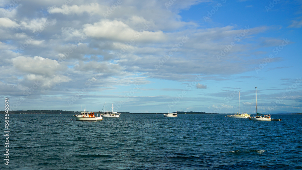 Yachts moored in the bay, beneath a beautiful blue cloudy sky. Coochiemudlo Island, Queensland, Australia. Yachts moored in the bay, beneath a beautiful blue cloudy sky. Coochiemudlo Island, Queensland, Australia.