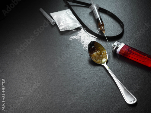 Obraz na plátně Ketamine on old spoon with cigarette lighter and syringe on black wood background