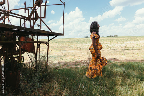 Woman on farm near vintage tobacco machine wearing modern African dress photo