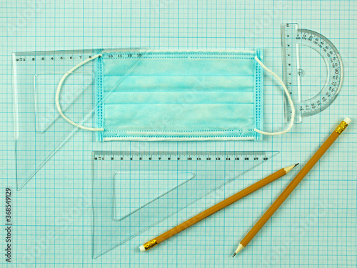 Back to school and a medical mask. social distance and education. scaled coordinate paper, ruler, protractor and pencil