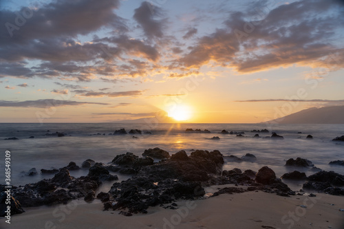 Sunset on beach in Hawaii Maui Long exposure of waves coming in with sand .