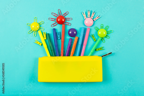 yellow pencil case and a set of bright colored markers for drawing and coloring on a blue background. Color palette.