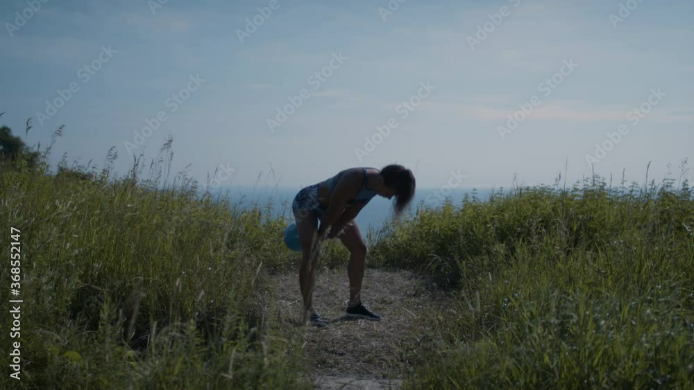 Powerful woman exercises on hilltop in order to achieve her goals. Focused and determined. Shot in 4k. 